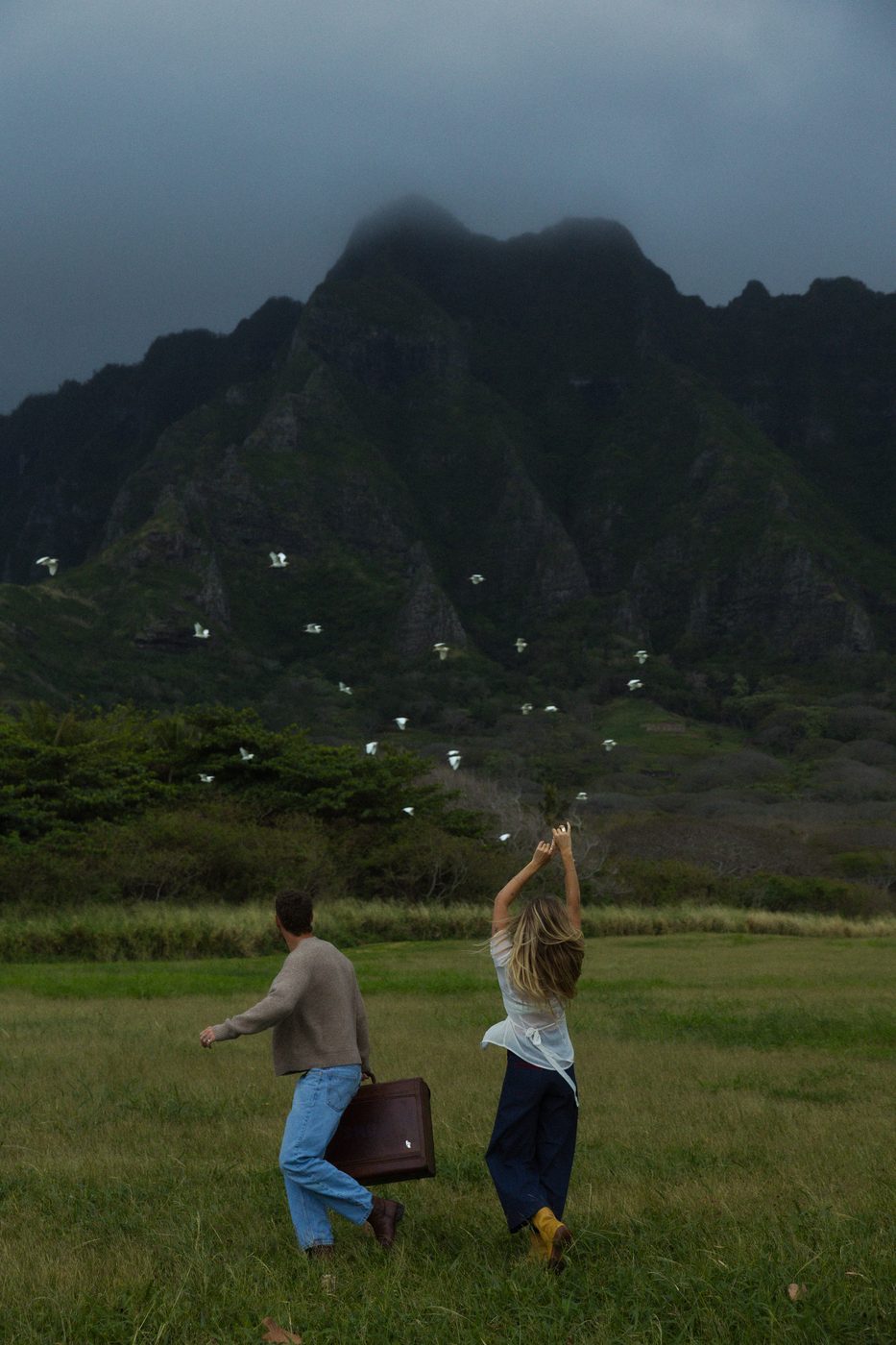 Couple with sparklers below a green Hawaiian mountain ridge