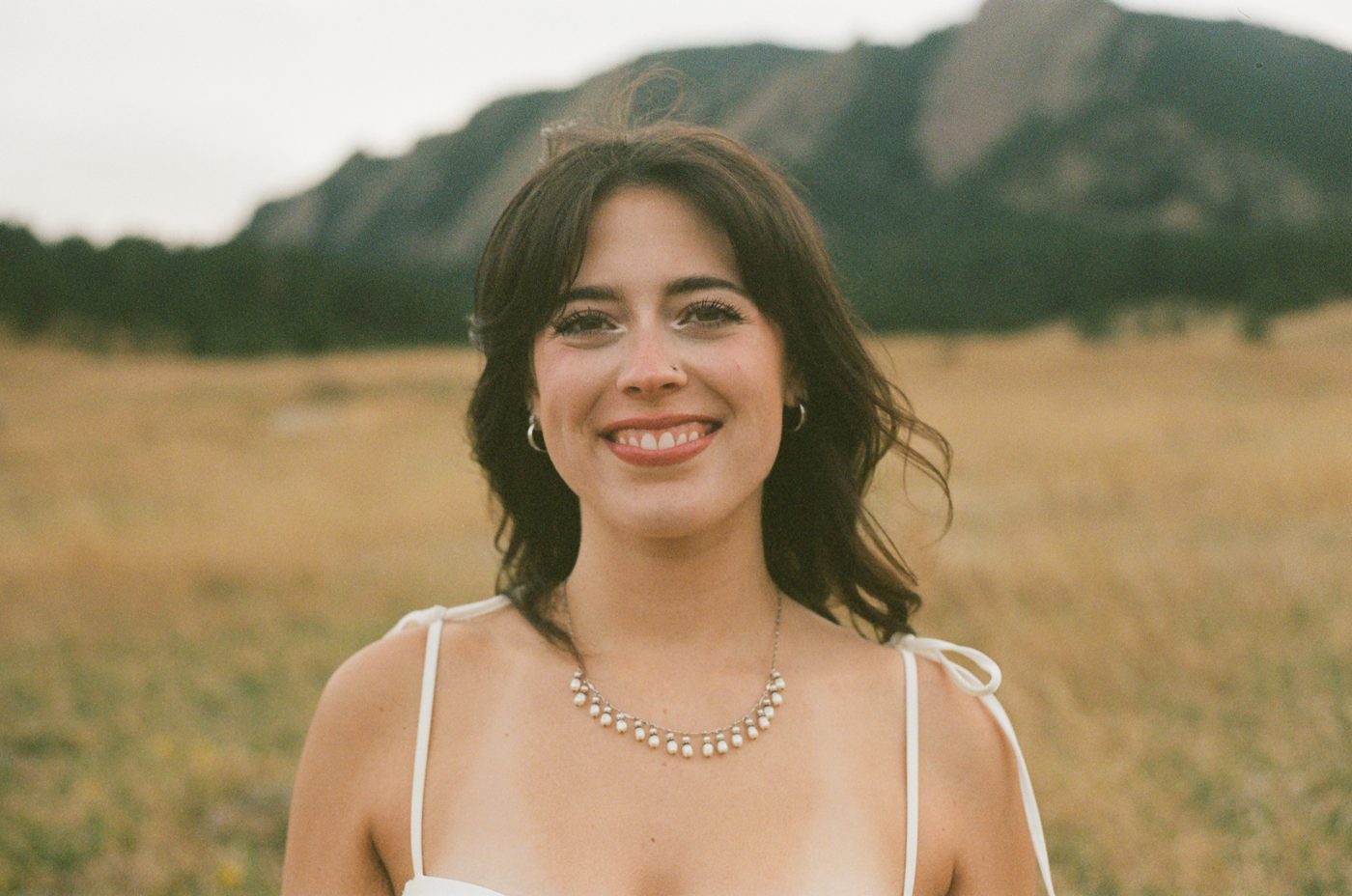 A smiling portrait in a golden meadow below the mountains