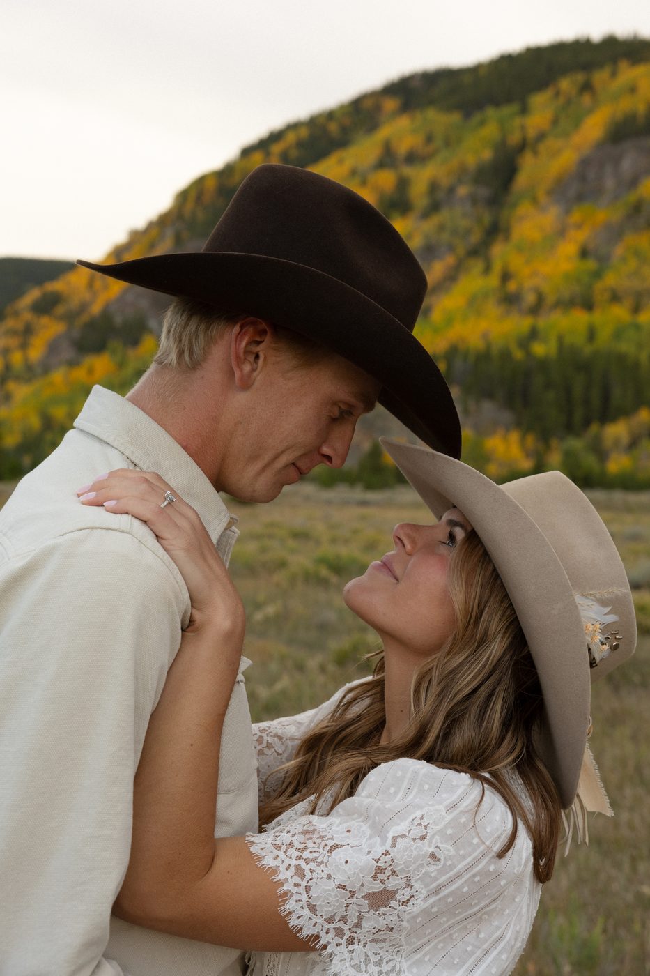 Couple in cowboy hats embracing among autumn aspens