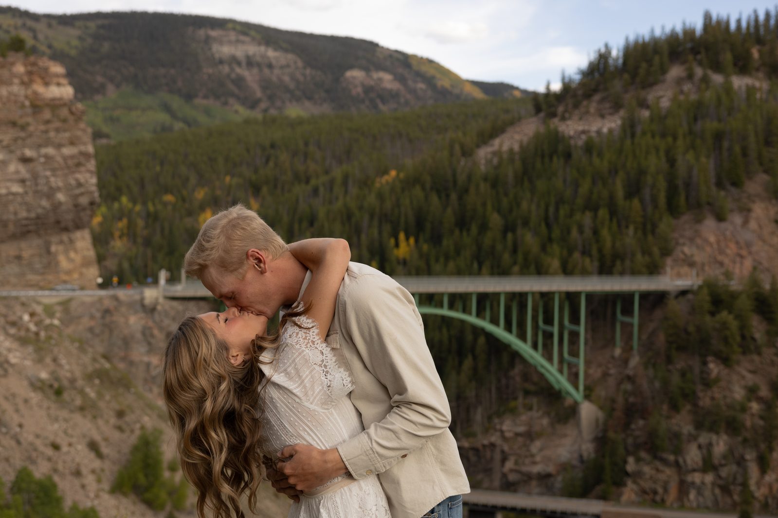 Couple kissing at a canyon overlook near a high bridge