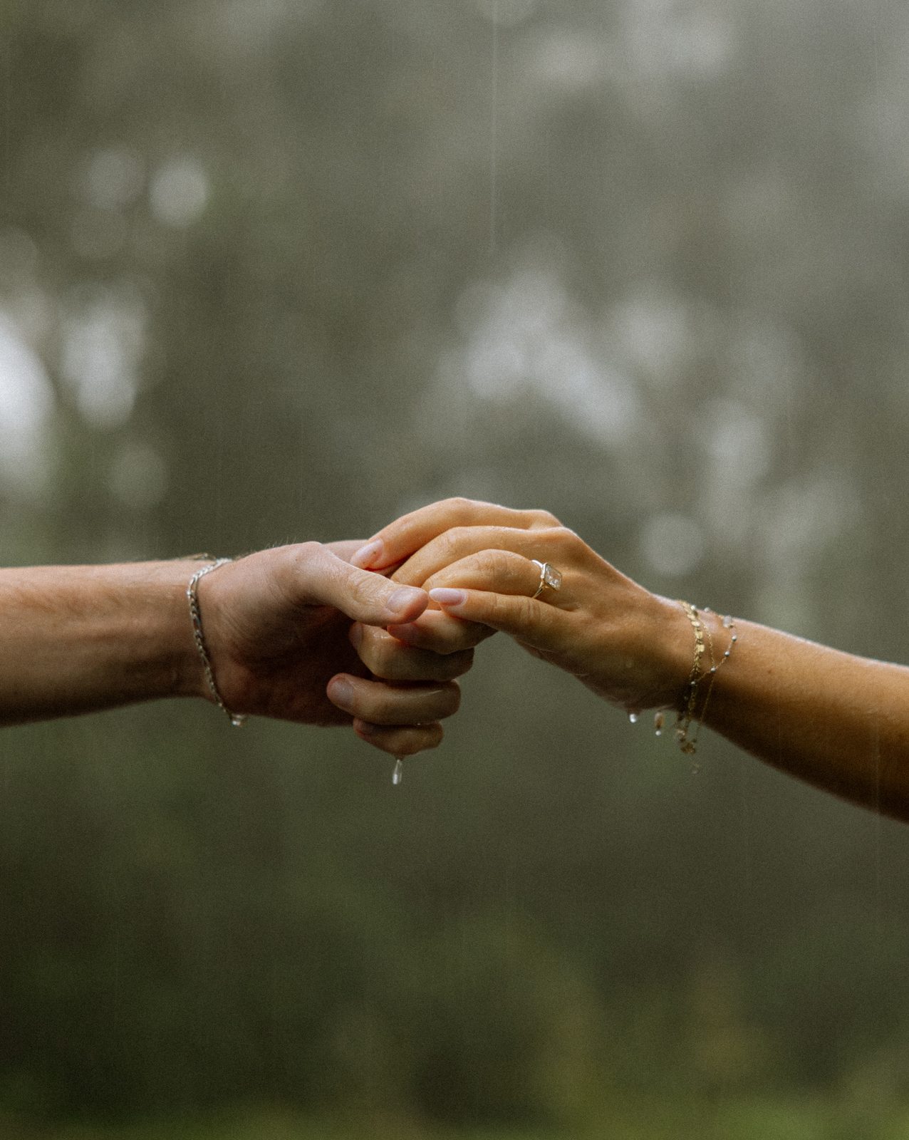 Two hands gently linked in soft rain